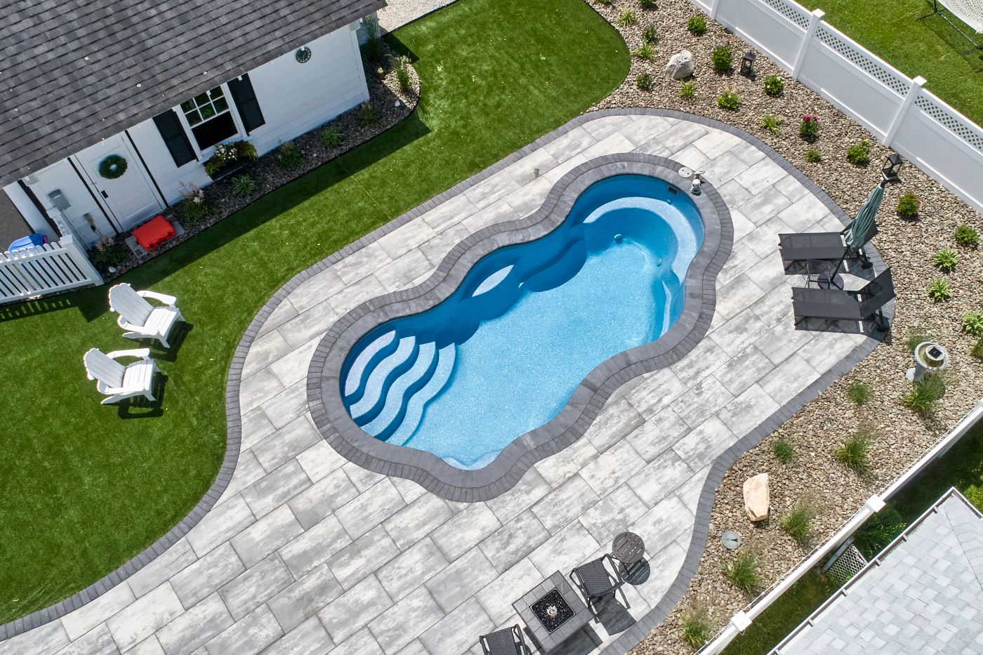 freeform fiberglass pool in small backyard with shed and patio furniture