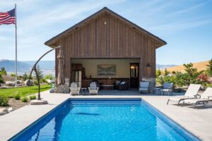 fiberglass pool installed on a hill in Washington backyard with pool house and plants