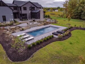 fiberglass pool with custom water features in northeast backyard