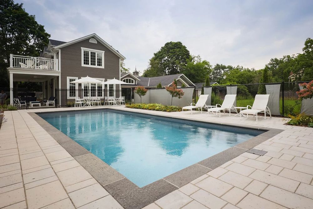 large fibreglass pool with safety fence in big Ontario backyard