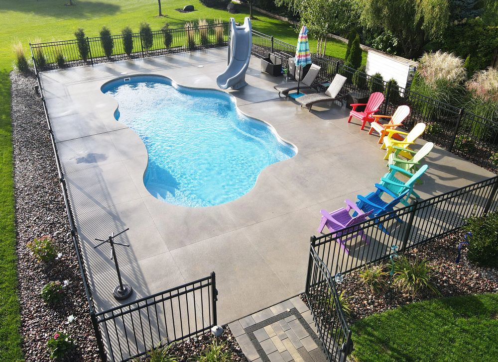 freeform fiberglass pool with curved pool slide and safety fence