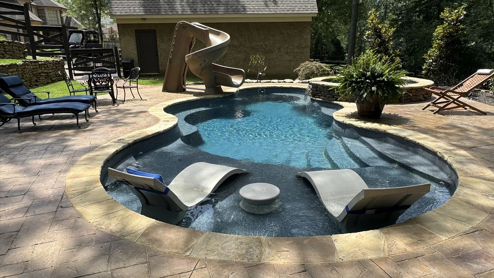 corkscrew pool slide installed in fiberglass pool with spillover spa and tanning ledge